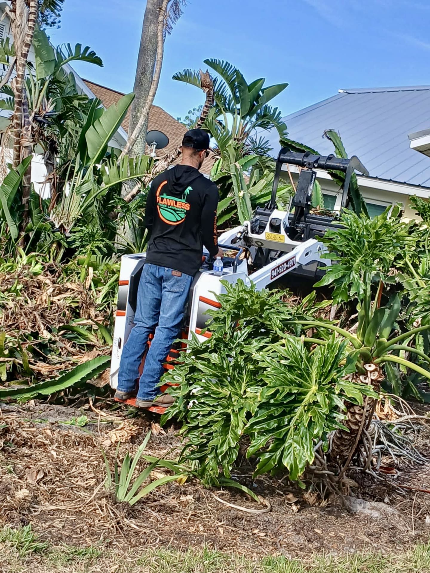 Crew member operating a bobcat during a major yard clearing and cleanup