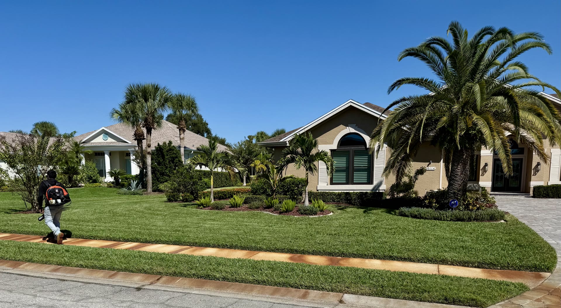 Flawless Palms crew mowing a beautiful Sarasota residential lawn with palms